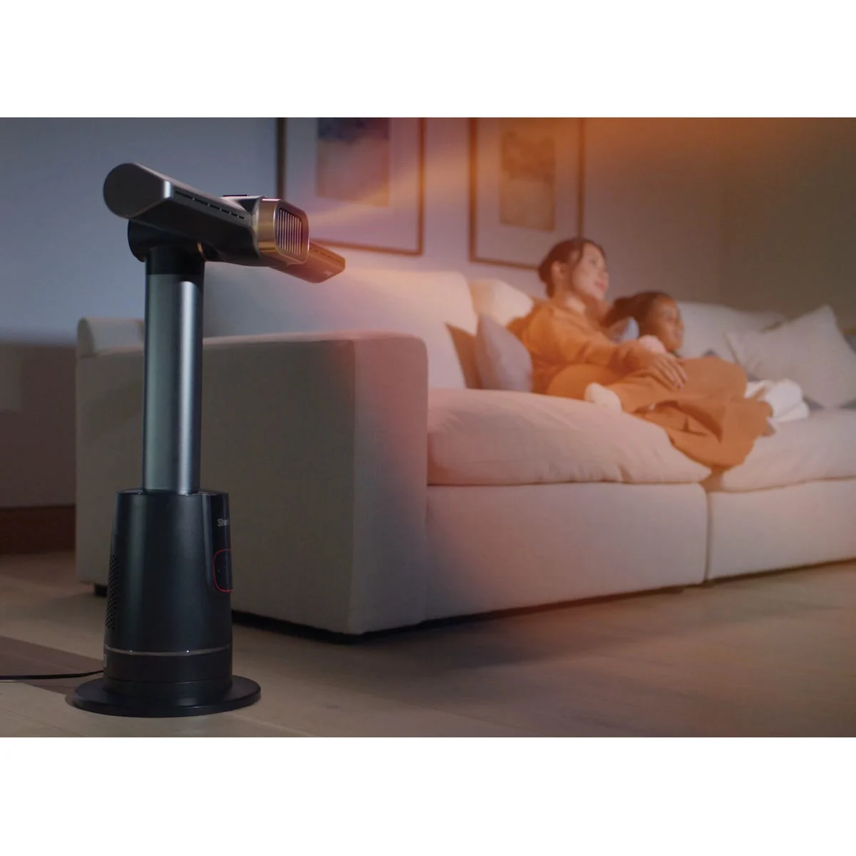Le Shark TurboBlade Cool + Heat anthracite chauffe le salon, une femme au chaud sur le canapé